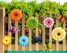 colorful flowers and butterflies are placed on a wooden fence