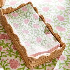 a wicker basket sitting on top of a pink and green table cloth covered table