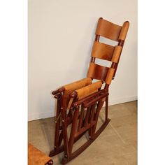 a wooden rocking chair sitting on top of a tile floor next to a white wall