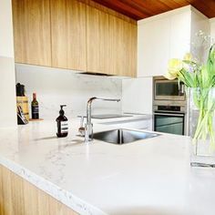 a vase with flowers sitting on top of a kitchen counter next to a sink and oven