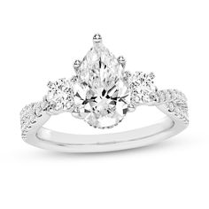 a pear shaped diamond engagement ring with three stones on the band and an oval center stone