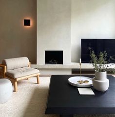 a living room with white furniture and a black coffee table in front of a fireplace