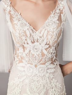 the back of a wedding dress with sheer sleeves and floral appliques on it