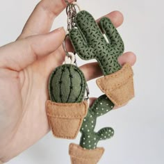 a hand holding a green cactus keychain in it's left hand,