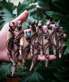 a person holding five different pieces of jewelry in their hand, each with turquoise stones