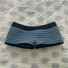 a blue and black knitted shorts laying on top of a white bedspread