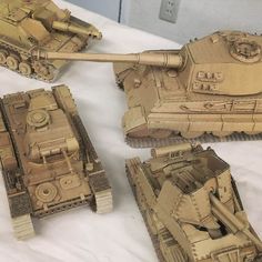 three toy tanks are on a white sheet