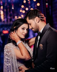 a bride and groom pose for a photo in front of the city lights at their wedding reception