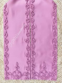 the back of a pink vest with an intricate design on it, sitting on top of a straw mat