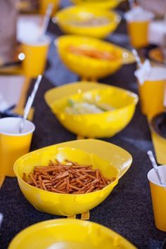 yellow bowls filled with food sitting on top of a table next to cups and spoons