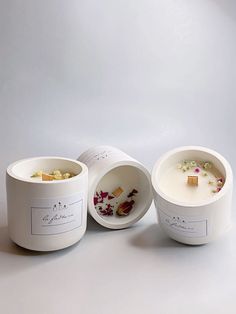 three white bowls with flowers in them sitting next to each other on a gray surface