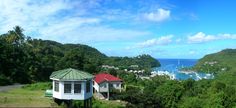 two small houses sit on top of a hill overlooking the ocean and boats in the water