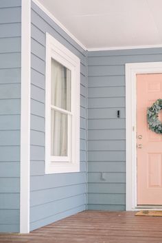 the front door of a blue house with a wreath on it's side entrance