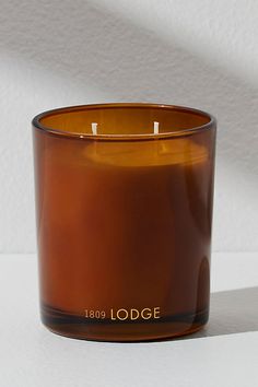 a brown candle sitting on top of a white table next to a wall with the words lodge written on it