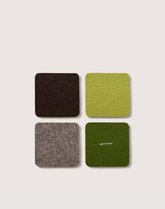 four square coasters with different colors and designs on the top one is green, brown, and grey