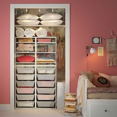 an organized closet with pink walls and white furniture in the corner is filled with linens