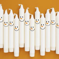 several white paper tubes with snowmen drawn on them and one is lined up in the same row