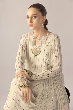 An ivory georgette long shirt with a draped dupatta is handworked with delicate kamdani. The sleeves and neckline are detailed with jewelled floral motifs. An elegant ensemble for any formal event or soiree. Elegant Off-white Dupatta For Reception, Elegant Off White Dupatta For Reception, Elegant Off White Palazzo Set With Traditional Drape, Off White Elegant Palazzo Set For Festive Season, Elegant Off White Festive Palazzo Set, Elegant Off White Palazzo Set For Festive Season, Festive Off White Elegant Palazzo Set, Elegant Off White Traditional Wear With Sheer Dupatta, Elegant Traditional Wear With Pearl Embroidery For Reception