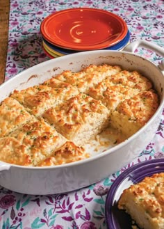 a casserole dish with cheese and bread in it on a floral tablecloth