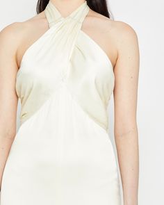 a woman wearing a white dress with an asymmetrical halter neckline