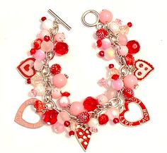 a red and white bracelet with hearts, charms and other items on top of it