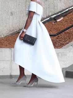 a woman in a white dress is walking down the street with her hand on her hip