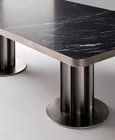 a black marble table with two silver pedestals