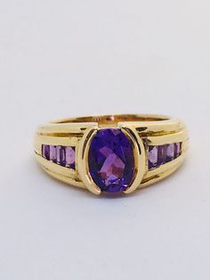 Superb 18ct gold ring set with a large amethyst gemstone. It has a beautiful diamond cut center stone and a cascade of baguette cut Amethysts on both sides. The metaphysical properties of Amethyst are calmness, balance, and peace. Amethyst is a meditative and calming stone that works on the emotional, spiritual, and physical planes. Amethyst has a certain luxurious quality being the royal purple. A natural tranquilizer amethyst relieves an individual from stress and strain, Amethyst is thought o Purple Ruby Ring For Formal Occasions, Classic Amethyst Ring Stamped 14k, Formal Purple Topaz Gemstone Ring, Classic Amethyst Purple Rings, Classic Purple Ruby Ring, Elegant Purple Amethyst Signet Ring, Formal Purple Ruby Ring, Classic Purple Gemstone Signet Ring, Classic Purple Signet Ring For Anniversary