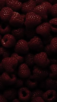 raspberries are piled up and ready to be eaten by someone in the dark