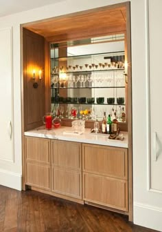 a bar with wine glasses and bottles on it in a room that has wood floors