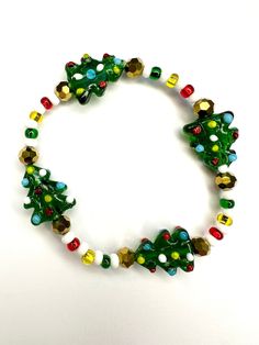 Rock around the Christmas tree with this glass beaded stretch bracelet. Glass seed beads add onto the bright colors of the tree making it the merriest accessory this holiday season!  Bracelets are available in a variety of lengths.  Pick your custom length from the drop down menu below.  Please be aware that beading may slightly differ from what is pictured as to accommodate selected sizing.  All our bracelets are made with quality in mind.  With that being said, all bracelets should be treated Festive Green Beaded Bracelets With Colorful Beads, Festive Green Beaded Bracelets, Festive Christmas Beads With Round Shape, Festive Christmas Beads, Christmas Festive Round Beads, Adjustable Colorful Beaded Bracelets For Christmas, Green Beaded Bracelets For Festive Occasions, Christmas Green Beaded Bracelets, Green Beaded Bracelets For Holiday