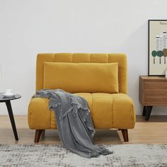 a yellow couch with a blanket on it next to a coffee table and end tables