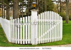 an old white picket fence in the park