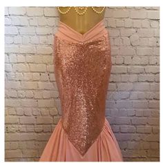 a pink dress with gold sequins on the neck and back, in front of a brick wall