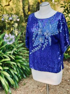 This is a vibrant blue floral sequin top blouse that is perfect with Jeans or a dressed up pant. The fabric is pure silk with sequin embellishment. This lovely top is made in India by Jasmine by K.V.M. Calif.  Measurements laying flat across: Pit to pit-22" Waist- 20" Length- 22.5" Sleeves- 13" Festive Embellished Blue Blouse, Festive Blue Embellished Blouse, Blue Fitted Silk Tops, Fitted Silk Blue Tops, Fitted Blue Silk Tops, Festive Blue Evening Blouse, Festive Evening Blue Blouse, Spring Embellished Silk Tops, Fitted Blue Embellished Blouse