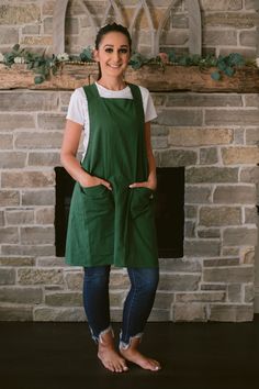 a woman standing in front of a brick fireplace with her hands on her hips and smiling