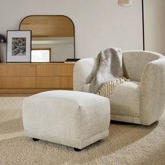 a chair and ottoman in a room with a mirror on the wall behind it,