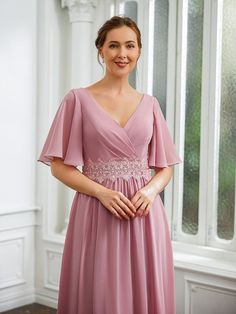 a woman in a pink dress posing for the camera with her hands on her hips