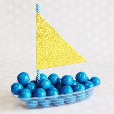 a plastic container filled with blue and yellow candies on top of a white table