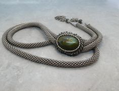 "The Labradorite Bolo Tie or Chunky lariat necklace made with silver seed beads is a stunning piece of jewelry that is sure to make a statement. The Labradorite gemstone is known for its iridescence and beautiful play of colors, which is further enhanced by the silver seed beads. Not only is this chunky lariat necklace beautiful, but it is also versatile as it can be worn in different ways. The lariat style allows for adjustable length and can be worn as a bolo tie or as a traditional necklace. The unique combination of the Labradorite gemstone and silver seed beads makes this labradorite bolo tie necklace a great addition to any outfit. It can be dressed up for a formal event or worn casually with a simple blouse and jeans. Overall, the Labradorite Bolo Tie necklace made with silver seed Handmade Artisan Silver Lariat Necklace, Artisan Handmade Silver Lariat Necklace, Unique Handmade Silver Lariat Necklace, Silver Artisan Lariat Necklace For Gift, Artisan Silver Lariat Necklace For Gift, Polished Beads Lariat Jewelry Gift, Polished Beads Lariat Jewelry For Gift, Adjustable Lariat Beaded Necklace With Polished Beads, Silver Lariat Necklace With Natural Stones