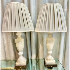 two white lamps sitting on top of a glass table