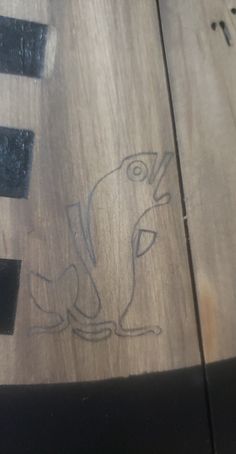 a wooden table with some drawings on the top and one has a bird drawn on it