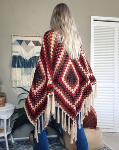 a woman wearing a red and white crocheted shawl with tassels