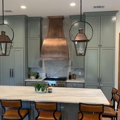 a large kitchen with an island and lots of chairs around the counter top, along with hanging lights