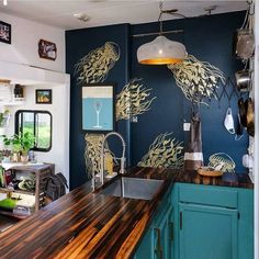 a kitchen with blue cabinets and wood counter tops in the center is decorated with gold leaves