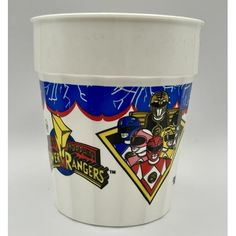 a white cup with some stickers on the side and an image of power rangers