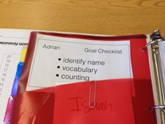 a red binder sitting on top of a wooden table