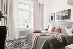 a bedroom with pink and grey bedding, zebra print rugs and pictures on the wall