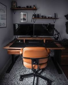 a desk with two monitors and a chair