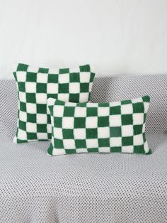 two green and white checkered pillows sitting on a couch next to a pillow case